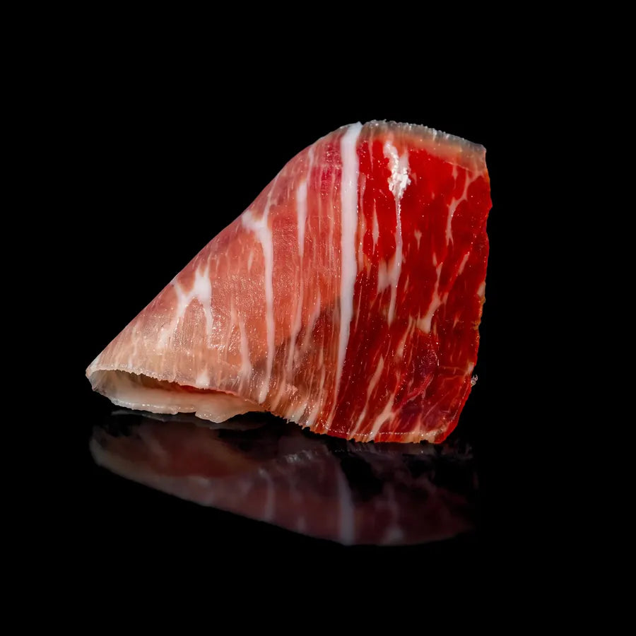 Loncha de jamón de bellota ibérico con grasa infiltrada y color rojo intenso